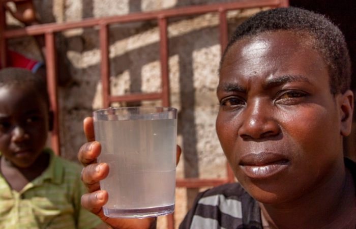 Priscilla holds a glass of dirty water in Lusaka, Zambia