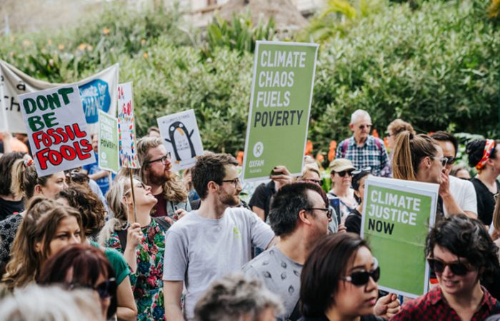 Protesters at the Melbourne #ClimateStrike holding signs that say "Climate Chaos Fules Poverty", "Climate Justice Now" and "Dont be Fossil Fools"