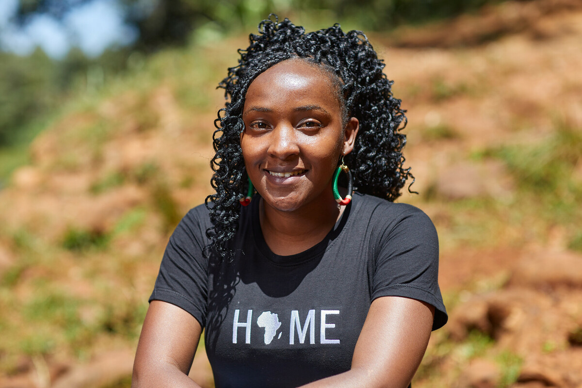 Elizabeth Wanjiru climate justice activist sits on a hill